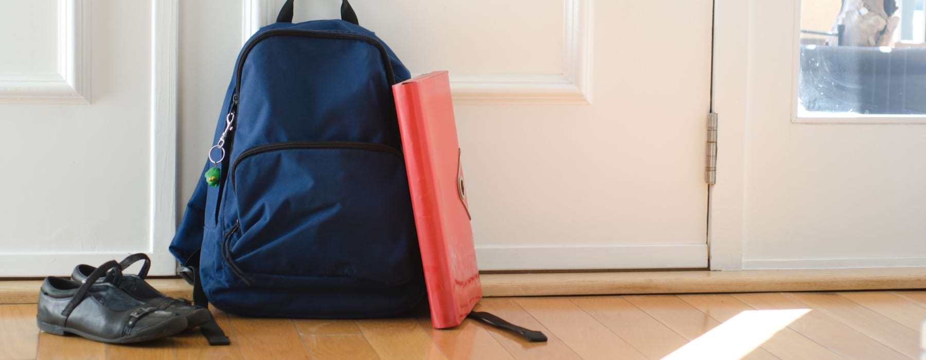 a bookbag, shoes and a binder on the floor