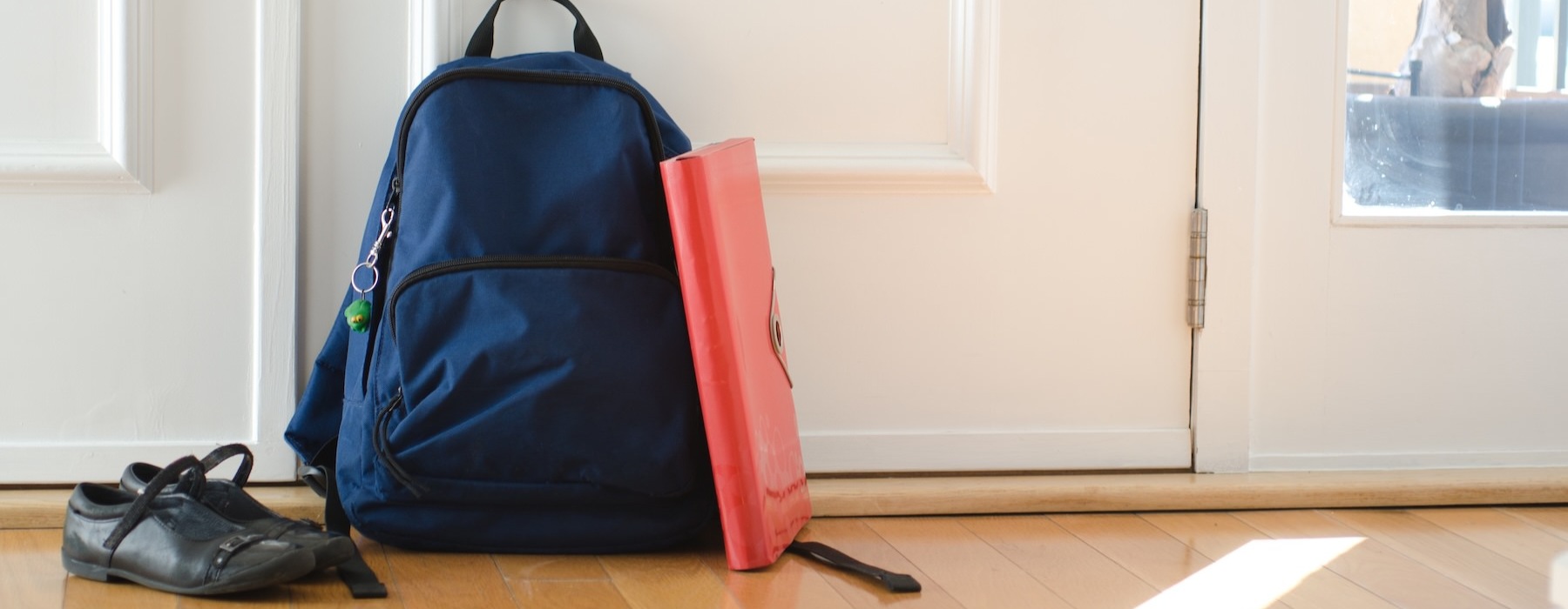 a bookbag, shoes and a binder on the floor